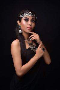 Stunning studio portrait of a woman showcasing intricate silver jewelry against a dark background.